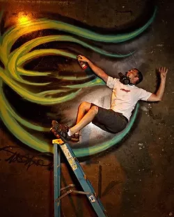 LIVING ON THE EDGE : In a photo shoot for New Times’ Autumn Arts Annual, graffiti artist Derek Brown feigned a terrible accident. The shoot was part of a series that recruited willing artists to toy with perspective: He’s actually lying on the ground. - PHOTO BY STEVE E. MILLER