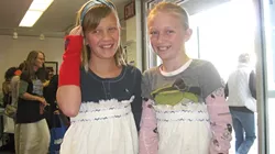 YOUNG SEAMSTRESSES : With the help of volunteers, friends Sabina Zink and Gretta Carlson fashioned differently styled dresses from the same curtain cloth. - PHOTO BY NICK POWELL