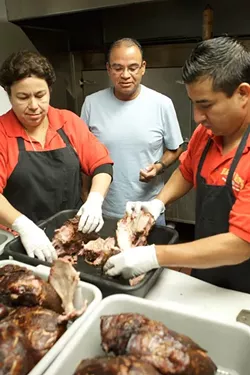 PORK-TASTIC! : Cowell (center) and colleagues Norma Moreno and Ricardo Perez are ready to pull pork for their renowned sandwiches. - PHOTO BY KATHY MARCKS HARDESTY