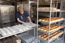 FERMENTED EDIBLES: Back Porch Bakery started out selling products literally on a porch, but now co-owner Dan Berkeland (prepping baguettes for the oven) makes many different types of bread for a variety of restaurants around the county. - PHOTO BY STEVE E. MILLER