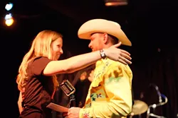 DOUBLE WINNER! : Downtown Brew’s Korie Newman (left), who acted as the NTMA emcee, embraces Red Eye Junction frontman Reid Cain, whose band won Best Song and got 2nd Best Band. - PHOTO BY STEVE E. MILLER