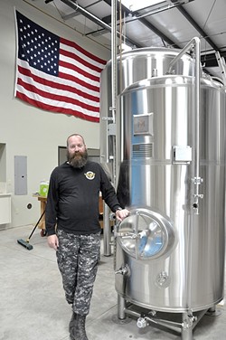BUILT TO SUIT:  Dunbar Brewing&rsquo;s Chris Chambers designed his new 10-barrel brewhouse, which was built by Paso Tank and Steel. The brite tank he&rsquo;s standing next to came out of Vancouver, Wash., and came complete with an American flag welded onto the side of it. Marks Metalworks added it specifically for Chambers, a veteran. - PHOTO BY CAMILLIA LANHAM
