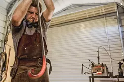 HOT STUFF: Using his anvil to steady the steel, Randolph slowly curves the end of it up. - PHOTO BY KAORI FUNAHASHI