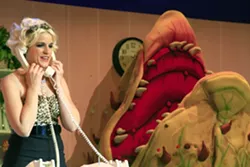 ‘CALL BACK IN THE MORNING’ : Audrey (Jennifer Malman) fields phone calls at Mushnik’s Skid Row Florists while Audrey II awaits her next victim. - PHOTO BY SANDRA CORTEZ