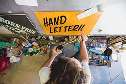 BETWEEN THE LINES: Bond retreats to his colorful Templeton garage/workspace, cranks the country, and hand paints signs till his knuckles ache. - PHOTO BY KAORI FUNAHASHI