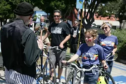 BLESSED! : The Jiminez family—(left to right) Mario, Sevryn, and Sherry—collectively get their bikes blessed. Sherry owns Salon 544 and organized the free family event. - PHOTO BY GLEN STARKEY