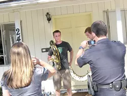 POSING : Police aided and abetted publicity surrounding the escape of a 23-foot-long python, but the fallout has been a problem for owner Brandon Dennis (with snake) and his roommates, including Elliot Barrington (left). - FILE PHOTO