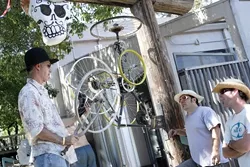 POSSE UP : Members of the Tall Bike Posse (from left to right) Bill Mulder, Dan Kallal, and Tim Gillham pondered the position of one more wheel on a whirly-gig contraption. - PHOTO BY STEVE E MILLER