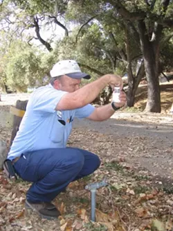 FAUCET FLOW : Drinking water is tested regularly, even at Lopez Lake campground, where Water Systems Operator Mark Woelfle fills a sample bottle. - PHOTO BY KATHY JOHNSTON