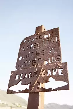 DON'T BE A LITTERBUG : A handmade sign above the cove offers directions, as well as a little insight into local customs. The beach functions almost without incident, and is maintained by the efforts of its regular sunbathers. - PHOTO BY STEVE E. MILLER