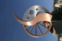 OLD AND NEW : For SLO metal artist Jeff Thies’ “Evidence of Evolution,� recently installed on Los Osos Valley Road near Madonna, he used materials — granite, teak wood, copper, stainless steel — that were maintenance-free and subject to graceful aging. The piece itself features a wagon wheel to represent the area’s Old West past, a copper flame to suggest the industrial revolution, and a contemporary stainless steel post-modernist element that looks to the future. - GLEN STARKEY