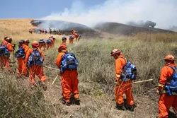 HEAT OF THE MOMENT : An inmate fire crew, led by California Department of Forestry officers (in the yellow suits), worked to safeguard a burned site from reigniting on Cuesta Grade. - PHOTO BY JESSE ACOSTA