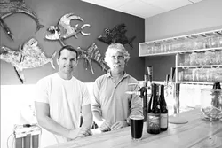 RAISING THE BAR : Mark London (right) opened SLO Down Pub in Arroyo Grande. SO-AND-SO (left) built the bar out of a fallen pine tree. The pub features locally produced alcohol, recycled fixtures, and a green heart. - PHOTO BY STEVE E. MILLER