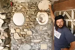 A MAN'S HOME IS HIS CASTLE : Mike O'Malley demonstrates how Nitt Witt Ridge reflects its creator's eccentricity, like Hearst Castle a-ways up Highway 1, but with more toilet seat de cor. - PHOTO BY STEVE E. MILLER