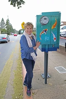 BELOVED KOI: Marcie Hawthorne stands next to a utility box she painted in 2010 as part of San Luis Obispo’s Box Art program. The city had plans to repaint several of the boxes, including this one, but changed course and will consider leaving some as they are. - PHOTO BY DYLAN HONEA-BAUMANN
