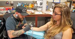 NO MUD, NO LOTUS: New Times Arts Editor Ryah Cooley’s sneaks a peek while Nik Blakhart of Sink or Swim Tattoo in Grover Beach works on a lotus flower design on her wrist. - PHOTO COURTESY OF RYAH COOLEY