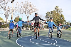 ALL TOGETHER NOW:  VonJon and handful of young unicycle enthusiasts link arms and pedal clockwise in unison at Meadow Park in San Luis Obispo. Led by Mark Wilder, the SLO Juggling and Unicycling Club has been gathering at the park to practice and learn for about five years. Wilder tries to provide individual coaching to each kid who comes on Tuesdays. &ldquo;That&rsquo;s what keeps them coming back,&rdquo; he said. - PHOTO BY DYLAN HONEA-BAUMANN
