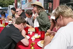 READY? GO! : The dozen or so contestants rip into plates of pancakes, except for Effie (standing), who makes a show of taking her sweet time because she’s just here for a free lunch. - PHOTO BY GLEN STARKEY