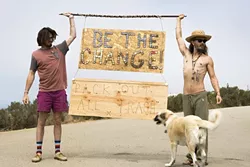 LEAVE NOTHING BUT MEMORIES: Nate Ross (left) and Logan Leggs (right), of Nomadic Artifacts, hold up a sign made from bottle caps that they collected at Pirate’s Cove. - PHOTO COURTESY OF VAGABOND INK.