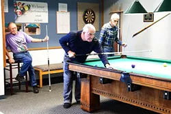 OUT AND ABOUT: Regulars at the 100-year-old pool table in the Morro Bay Senior Center are left to right: Wayne Gillmore, 79, Peter Gabriel, 66, and Rey Hudson, 85. They play pool for about three hours every day. Centers like this one help provide opportunities for SLO County seniors to stay active and engaged in their community. - PHOTO BY JAYSON MELLOM