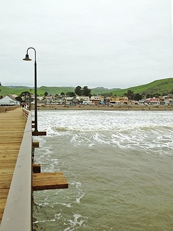 PIER-ING BACK:  The view from the end of the Cayucos pier back to shore was magnificent: bright green rolling hills and the funky beach town of Caycuos in the foreground. - PHOTO BY PETER JOHNSON