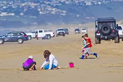 SAND, SUN, VEHICLES: Children play on the strip of beach between Pier Avenue and Arroyo Grande Creek, the sandy road that takes drivers to the 1,500 acres of Oceano Dunes that are available for off-road recreation and camping. - PHOTO BY JAYSON MELLOM