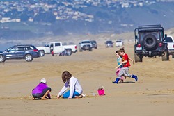 SAND, SUN, VEHICLES:  Children play on the strip of beach between Pier Avenue and Arroyo Grande Creek, the sandy road that takes drivers to the 1,500 acres of Oceano Dunes that are available for off-road recreation and camping. - PHOTO BY JAYSON MELLOM