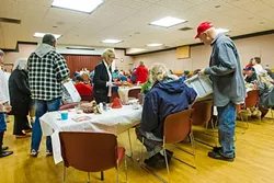 CHRISTMAS CHEER: Morro Bay City Council members Robert Davis (right) and Marlys McPherson (center) give out hats and cookies to attendees at a community dinner in Morro Bay the week of Christmas. - PHOTO BY JAYSON MELLOM