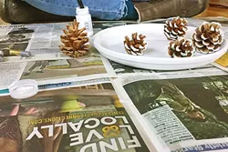 FUN WITH PINECONES: New Times makes a great community newspaper and a nice protective layer while painting pine cones. These guys made their way to the tree as ornaments. - PHOTO BY PETER JOHNSON