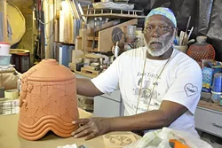 STACK IT UP : Alonzo Allen Jr. talks about how he creates his ceramic pieces, such as this bell that is waiting for spots of color and glaze. - PHOTO BY CAMILLIA LANHAM