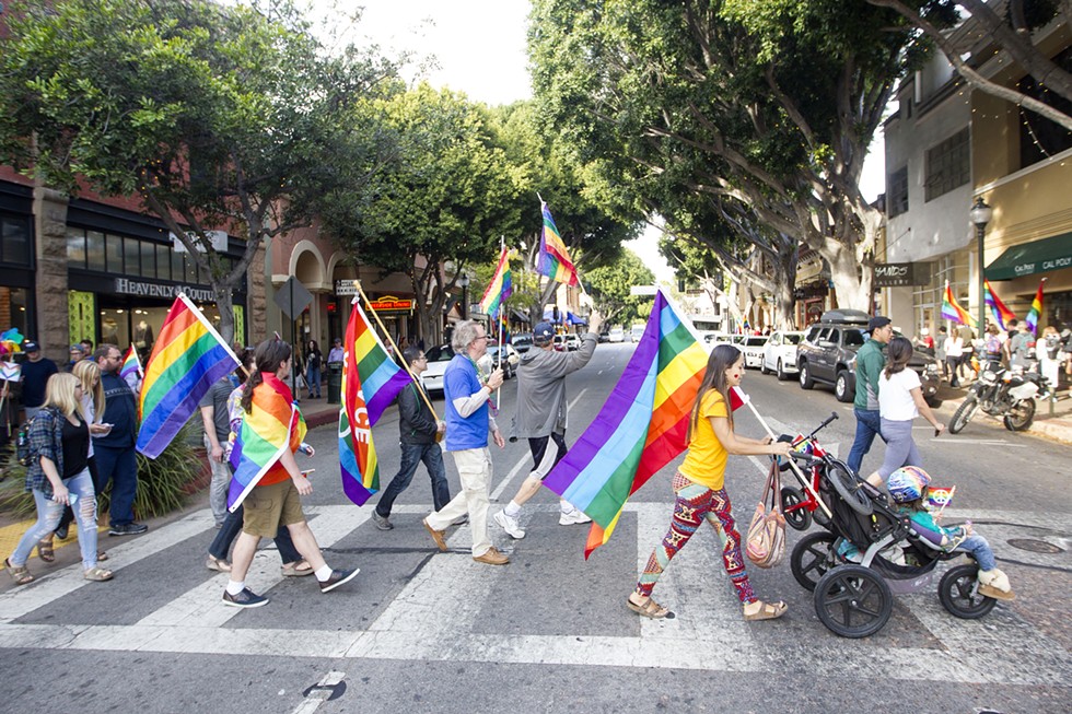 TASTE THE RAINBOW A group of demonstrators crosses Higuera Street in Downtown SLO during the “Show Your True Colors” rally. - PHOTO BY JASON MELLOM