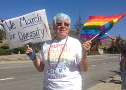 SUPPORTING TRANS TROOPS Carroll Leslie of Los Osos joined a crowd rallying for the rights of transgender military service members and veterans outside the SLO County Veteran's Memorial building on July 31. - PHOTO BY CHRIS MCGUINNESS
