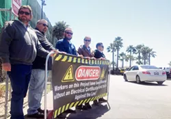 IN THE STREETS Members of IBEW Local 639 hold a banner at the construction site of a Pismo Beach hotel to protest the use of uncertified electricians. - PHOTO BY CHRIS MCGUINNESS