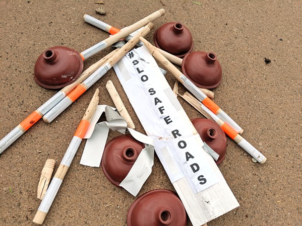 TOPPLED Demonstrators' temporary bike lane barriers lie in a pile on Aug. 28. After SLO bike advocates installed plungers as lane delineators on three busy streets, cars hit and destroyed many of them, according to participants. - COURTESY PHOTO