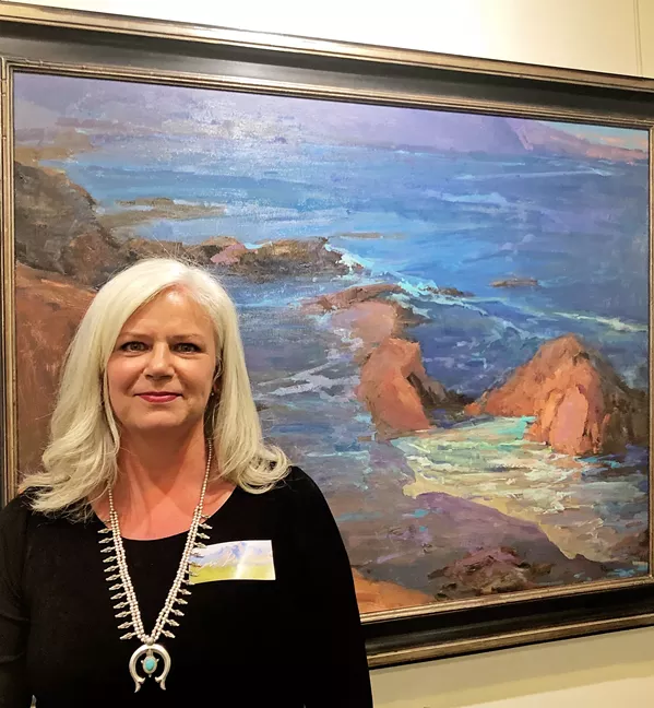 CONTEMPORARY GREATS Lori Putnam stands with her work titled Harmony Headlands. Her inspiration, Edgar Payne's Dana Point, is hung right next to Putnam's modern take. - PHOTO BY MALEA MARTIN