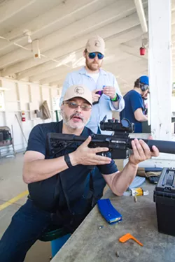 SAFETY LESSON Safety instructor and The Liberal Gun Club Executive Director Ed Gardner gives a lesson on how to properly and safely handle this variant of the AR-15, which was modified to shoot .22 caliber bullets and is 10 percent as powerful as a regular AR-15. - PHOTO BY JAYSON MELLOM