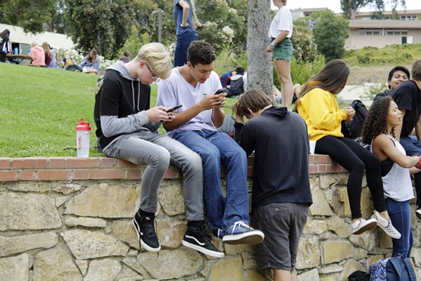 TTYL SLO High School students check their phones at lunch in 2019. The Paso Robles board of education is considering a new electronic device policy that would prohibit the use of cellphones, smart watches, and other mobile devices at all district sites during instructional time. - FILE PHOTO BY KASEY BUBNASH