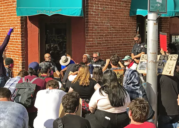 BLACK LIVES MATTER Protesters kneel with police on June 2 in Paso Robles as local business owner Oddette Augustus leads the group in a prayer. The moment marked the end of a six-hour protest against police brutality. - PHOTO BY PETER JOHNSON
