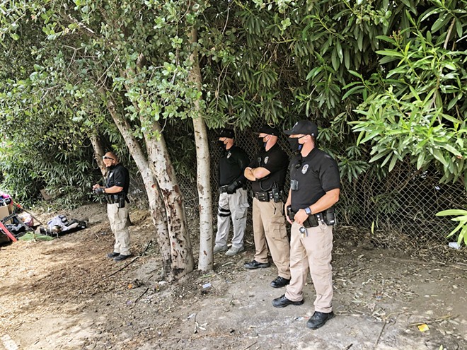 CLEARED OUT SLO police officers stand by as residents of the Bob Jones homeless camp clear out on May 18.