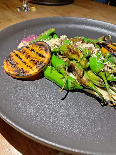FOR SHARING Shishito peppers cover a toasted sesame aioli alongside grilled orange and topped with merlot salt. - PHOTO BY CAMILLIA LANHAM