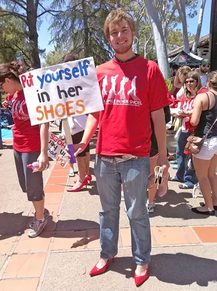 PRETTY IN RED : Our hero, Nick Powell, dons four-inch high heels to make his butt look nice. There also appears to be a fundraiser of some sort in the background. - PHOTO COURTESY OF WENDY-MARIE FOERSTER