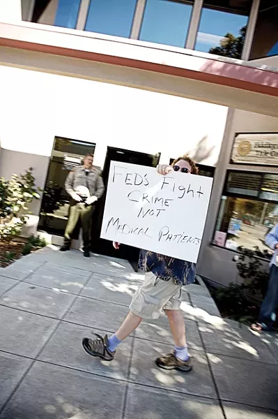 ONE-MAN PROTEST : As law enforcement agents wrapped up a raid in March 2007, Kent Connela paced the sidewalk with his homemade sign. “You guys are no better than a gang,” he said. “Waste of taxpayers’ money, man.” - FILE PHOTO
