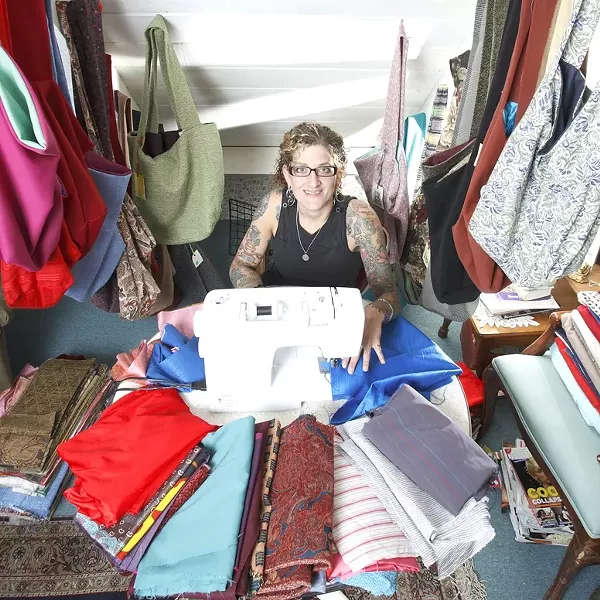 CAN’T SEEM TO GET ENOUGH : Ellen Baxter sits surrounded by her bags, which are selling like hotcakes in several San Luis Obispo locations. - PHOTO BY STEVE E. MILLER