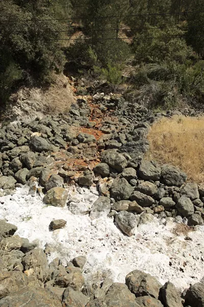LEFTOVERS : Red and white dust coats the ground at the Klau/Buena Vista Mine outside Paso Robles. The color comes from iron oxides and mineral salts left from contaminated runoff from mercury mine tailings. - PHOTO BY STEVE E. MILLER