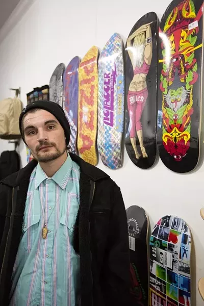 INSPECTAH DECK: Jake Johnson stands in front of the many custom skateboards at PMA Retail Gallery, where he will be showing his art and neverbefore-seen music video. - PHOTO BY KAORI FUNAHASHI