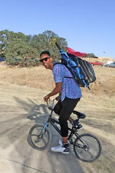 FAMOUS AMONG THE CROWD : One of the main stage performers at LIB this year, Lafa Taylor, is one of the smart ones who brought his bike to get around the vast space that the festival is held on. - PHOTO BY DYLAN HONEA-BAUMANN