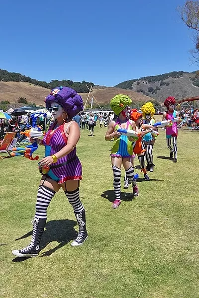STAY COOL: A cadre of squirt-gun-toting neon clowns keep attendees cool with a few well-placed water streams. - PHOTO BY GLEN STARKEY