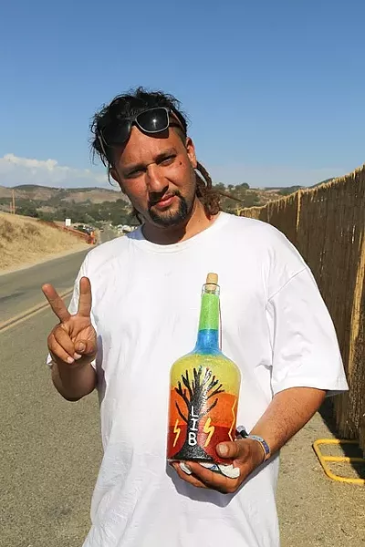 LIGHTNING IN A GIFT : Mike Dominguez holds up a hand-painted bottle given to him by a woman at LIB. Dominguez believes that LIB is part of the “Hopi prophecy of us rebelling against what was created and trying to create something new for the future of our children, for the future of humans.” - PHOTO BY DYLAN HONEA-BAUMANN