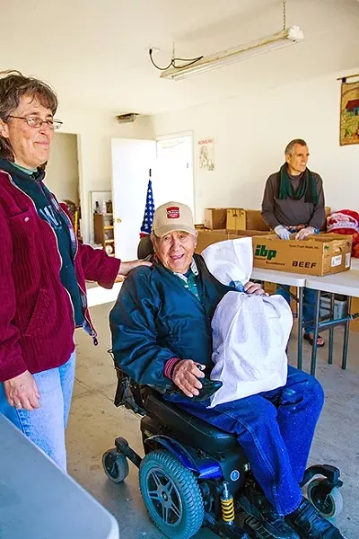 A LITTLE SECURITY: A man named Bendo receives a bag of food from Tensie Hernandez at the Catholic Worker in Guadalupe. - PHOTO BY JAYSON MELLOM