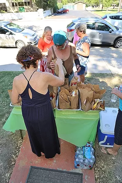 HELPING OUT: A volunteer with the Second Baptist Church hands out dinner to a man who needs it in June. The meal service, called the People’s Kitchen, closed in August after 30 years. - FILE PHOTO BY DYLAN HONEA-BAUMANN